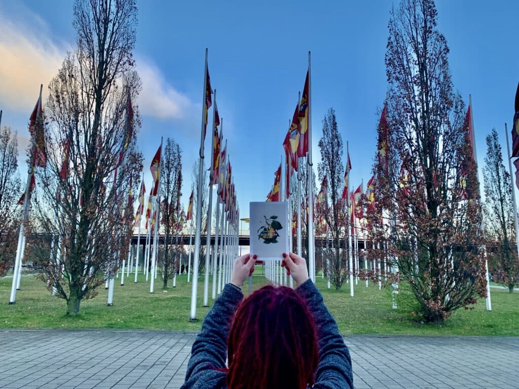 Person fotografiert das Leipziger Messegelände mit Fahnen vor blauem Himmel