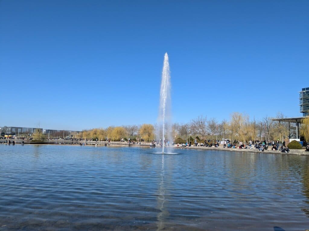 Wasserfontäne und Fahnen vor blauem Himmel auf dem Leipziger Messegelände
